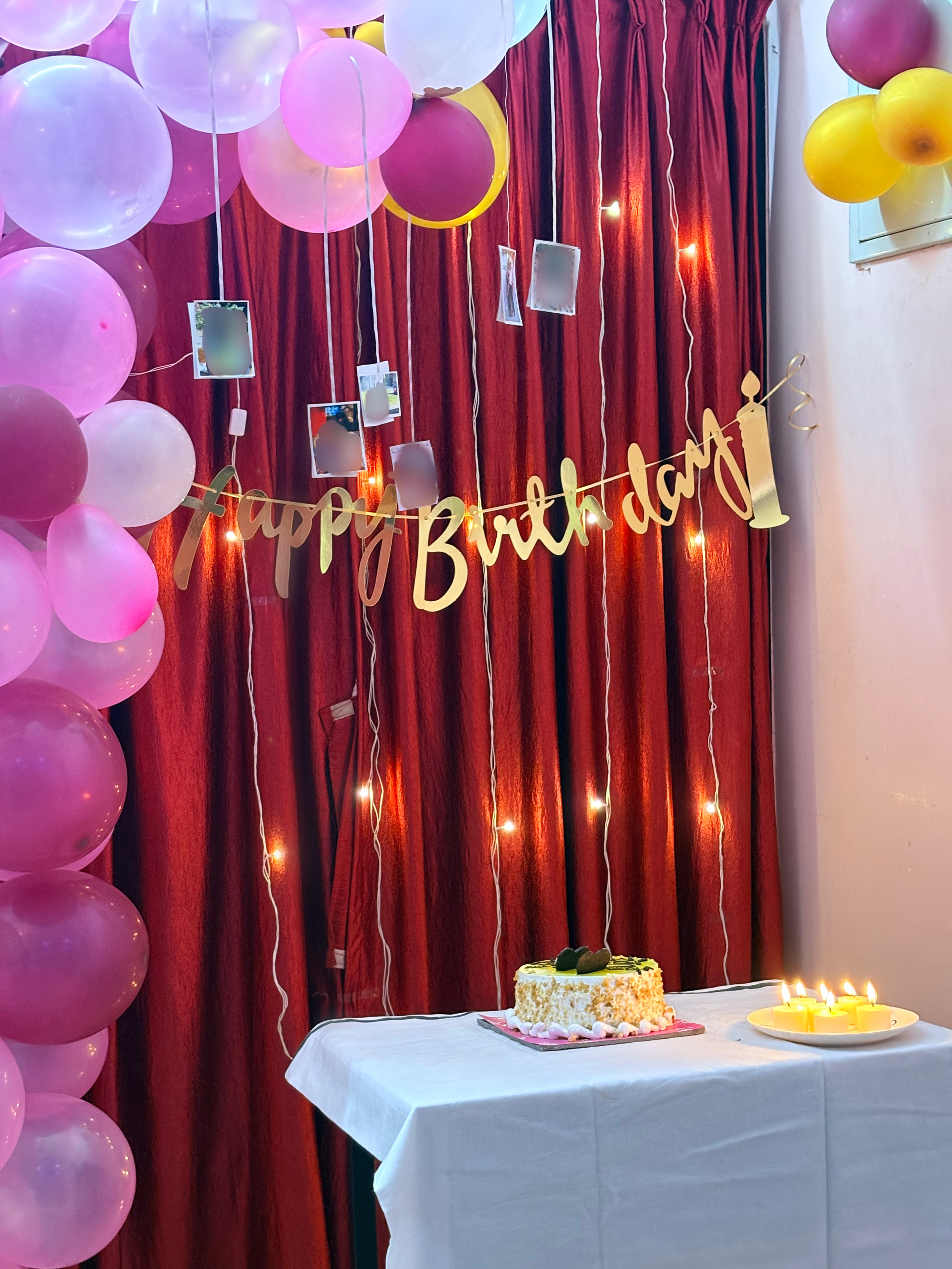 Room decorated with a happy birthday banner, balloons, cake and candles