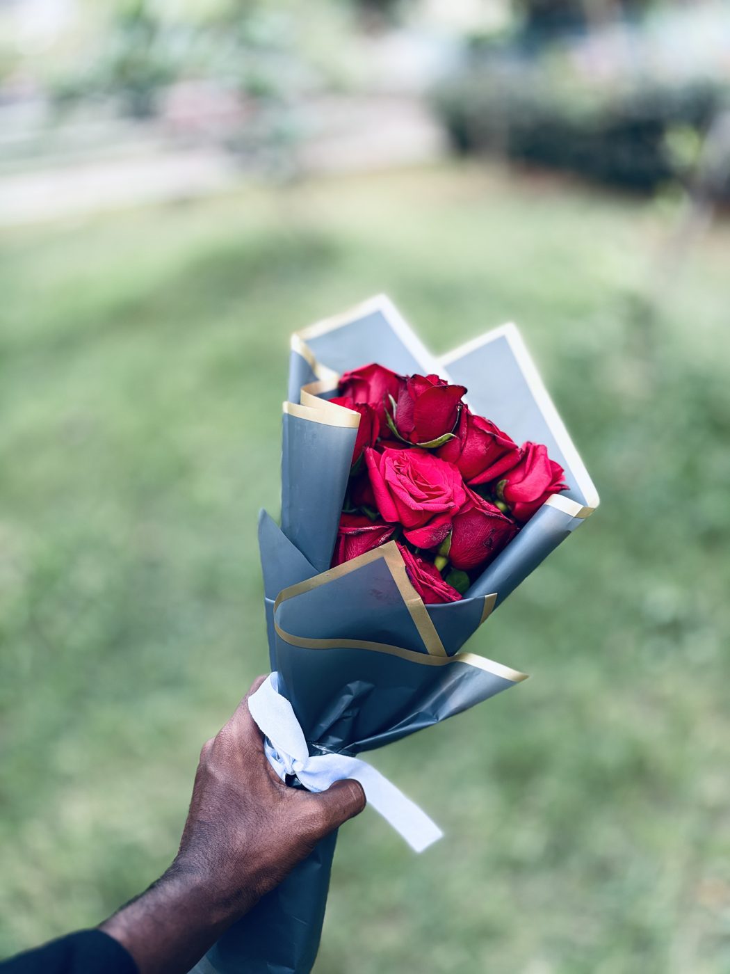 Hand-tied bouquet of red roses wrapped in grey and gold paper